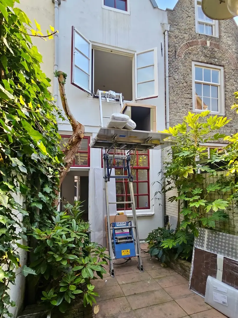 GEDA opbouwlift hijst een matras via een binnentuin naar het raam op de verdieping