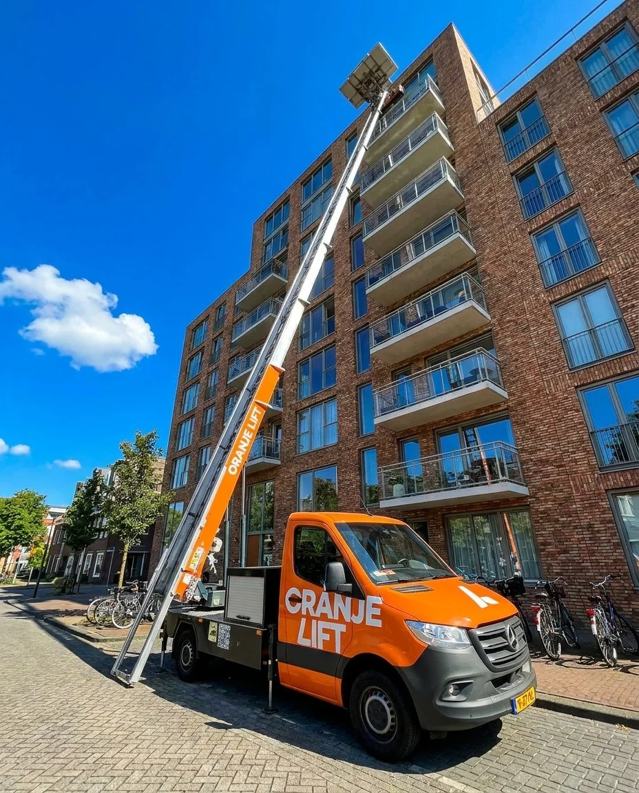 OranjeLift verhuisliftwagen met de ladder uitgeschoven tot de bovenste verdieping van een flat
